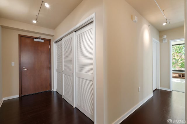 corridor with track lighting and dark wood-type flooring