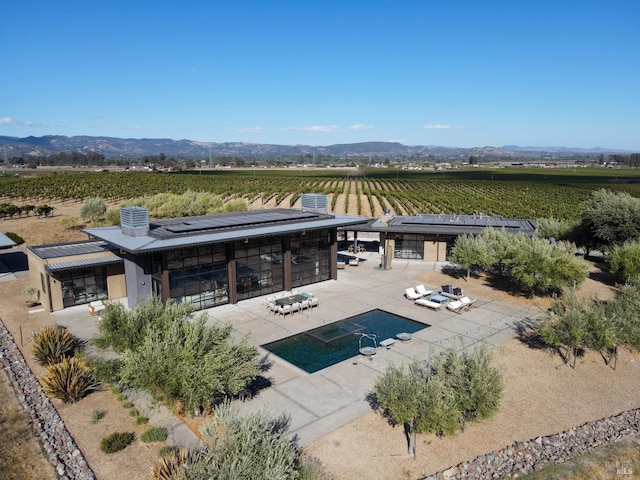 back of house featuring a patio area, a mountain view, and a rural view