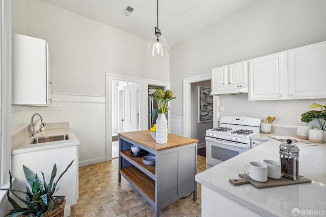 436 Page St, San Francisco, CA 94102 - kitchen with white gas range oven, a sink, under cabinet range hood, wooden counters, and white cabinets