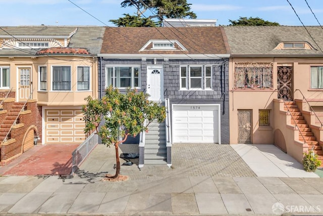 townhome / multi-family property with stucco siding, driveway, entry steps, roof with shingles, and an attached garage