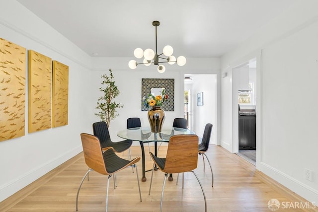 dining space with an inviting chandelier, baseboards, and light wood-style floors