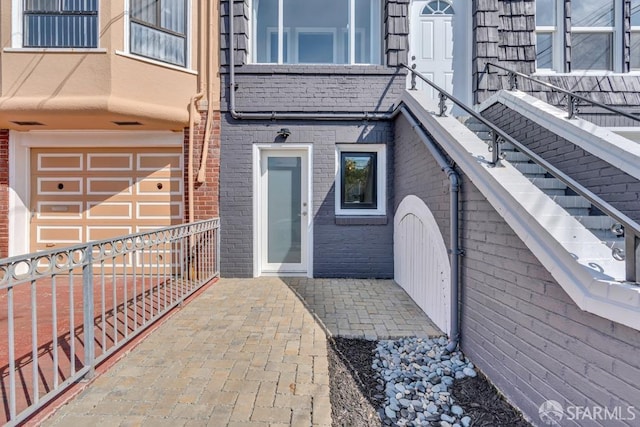 property entrance featuring an attached garage and brick siding