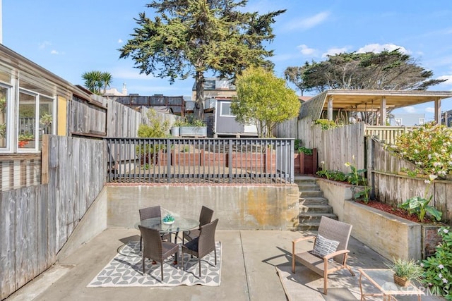 view of patio featuring stairway, outdoor dining space, and a fenced backyard