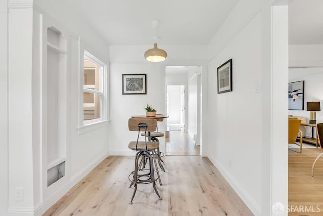 corridor with light wood finished floors and baseboards