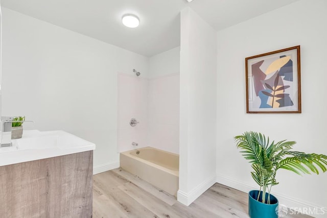 bathroom featuring baseboards, shower / washtub combination, wood finished floors, and vanity