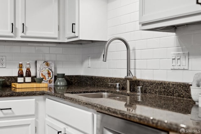 kitchen featuring tasteful backsplash, a sink, and white cabinets