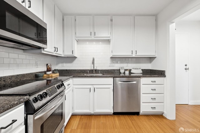 kitchen with light wood-style flooring, decorative backsplash, stainless steel appliances, and a sink