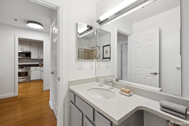 bathroom featuring tasteful backsplash, wood finished floors, and vanity