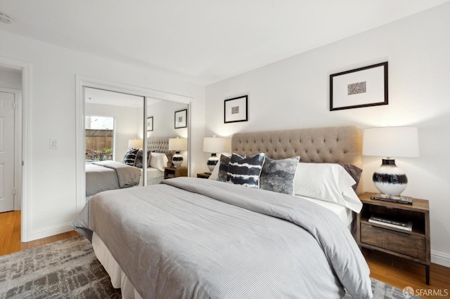 bedroom featuring a closet, wood finished floors, and baseboards