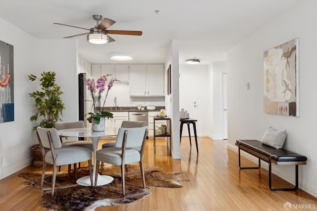 dining room featuring a ceiling fan, baseboards, and light wood finished floors