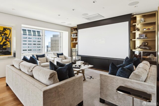 home theater room featuring built in features, wood finished floors, and visible vents