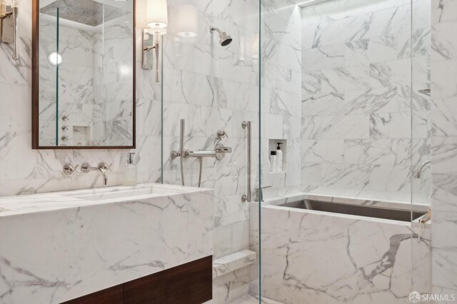 bathroom with a tub with marble appearance, a marble finish shower, and vanity