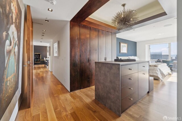 hallway with an inviting chandelier and light wood-style flooring