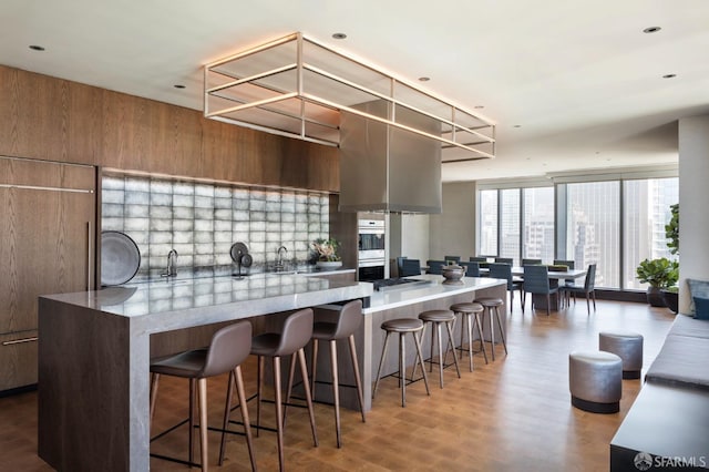 kitchen with a breakfast bar, brown cabinetry, modern cabinets, and wood finished floors