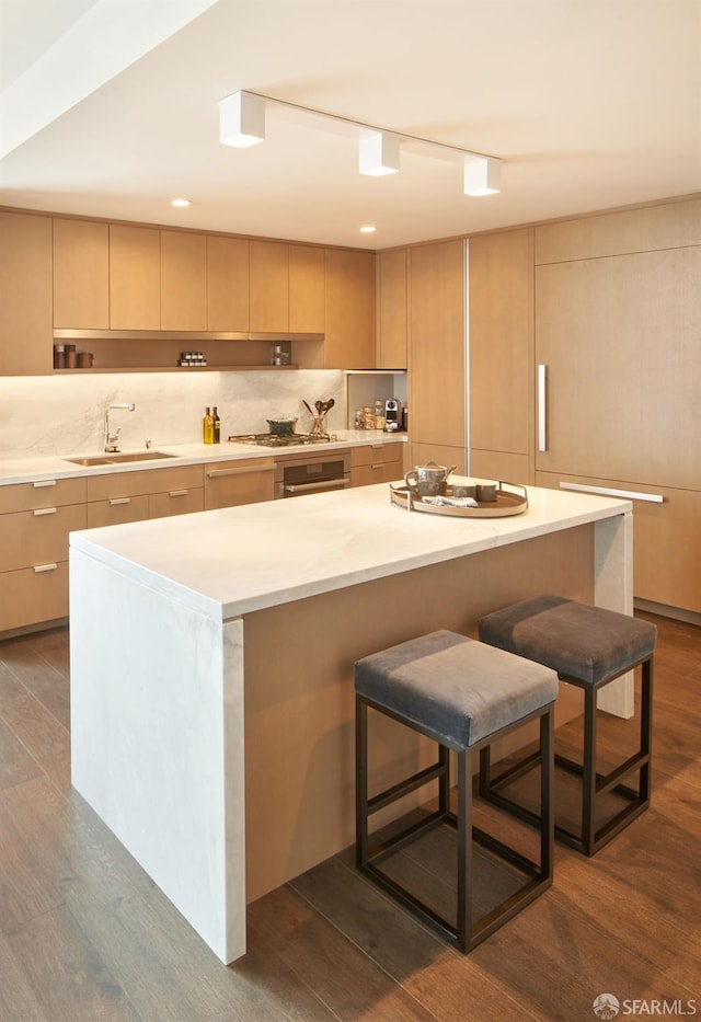 kitchen featuring a kitchen bar, modern cabinets, dark wood finished floors, and a sink