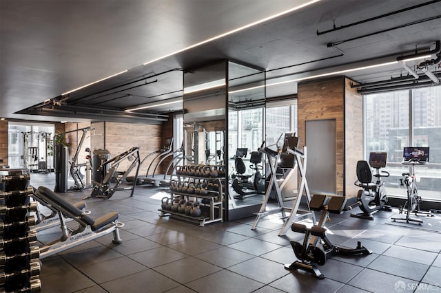 gym featuring wood walls and a wall of windows