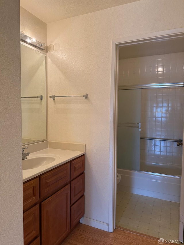 full bathroom featuring vanity, enclosed tub / shower combo, and toilet