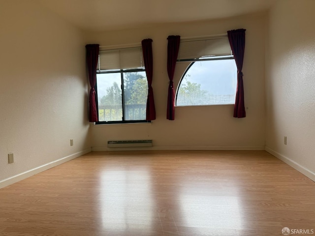 unfurnished room featuring light hardwood / wood-style flooring and a baseboard radiator