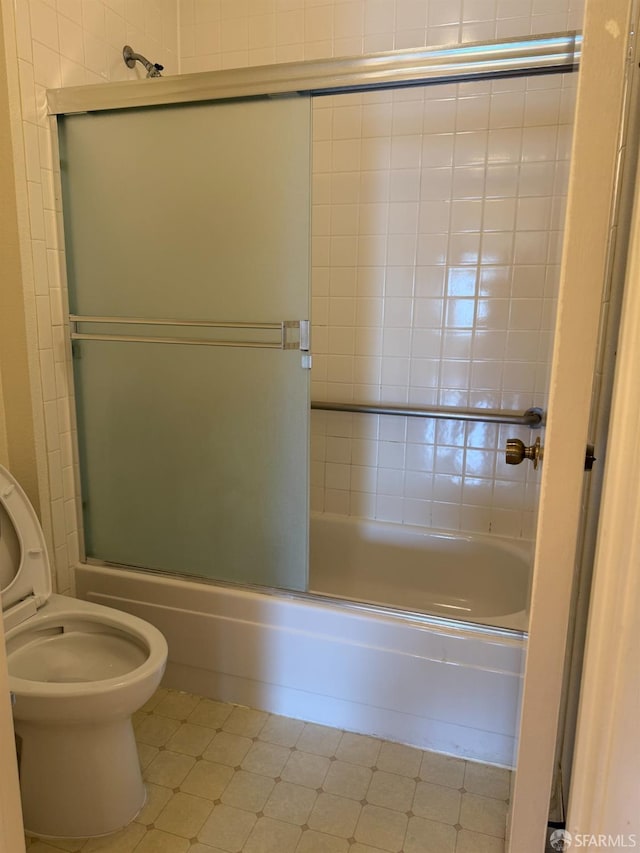 bathroom featuring combined bath / shower with glass door and toilet