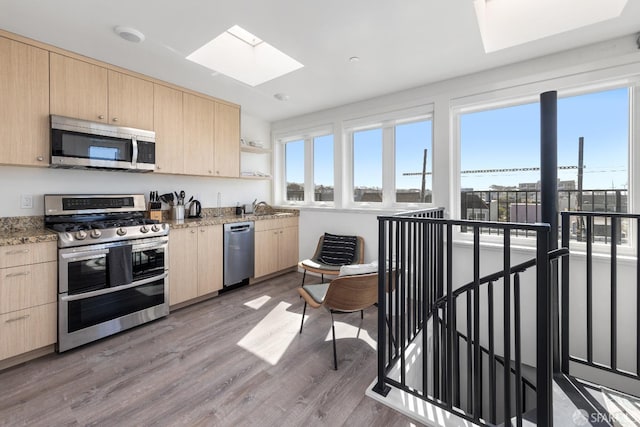 kitchen with appliances with stainless steel finishes, light brown cabinets, and light wood-type flooring