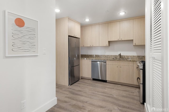 kitchen featuring sink, appliances with stainless steel finishes, light stone counters, light hardwood / wood-style floors, and light brown cabinetry