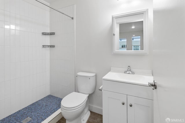 bathroom featuring tiled shower, vanity, and toilet