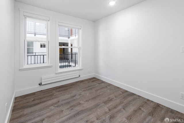 empty room featuring radiator and hardwood / wood-style flooring