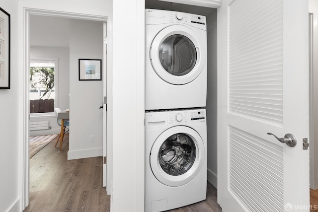 laundry area featuring stacked washer and dryer and wood-type flooring