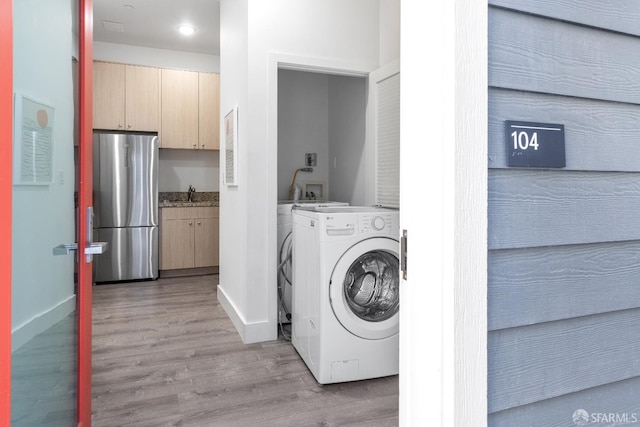 washroom with washer / dryer, sink, and light hardwood / wood-style flooring