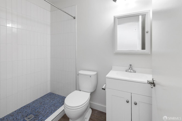 bathroom featuring vanity, toilet, and a tile shower