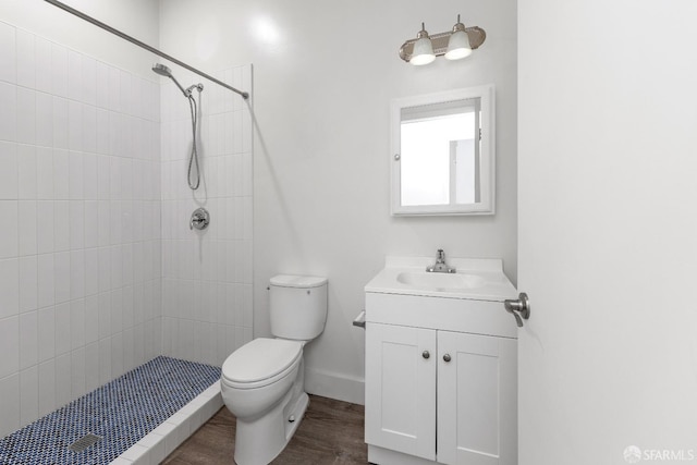 bathroom with vanity, wood-type flooring, tiled shower, and toilet