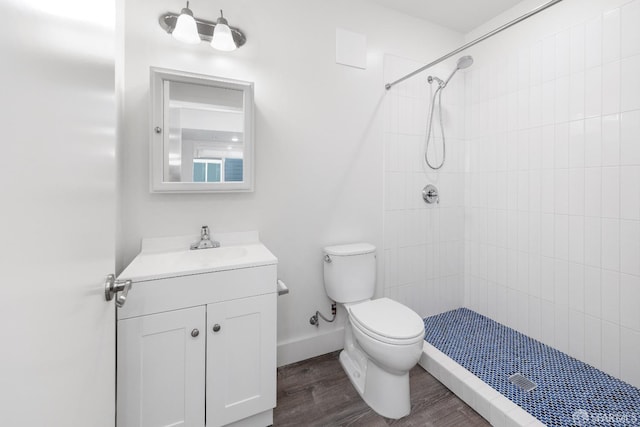 bathroom with vanity, wood-type flooring, toilet, and tiled shower