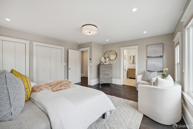 bedroom with dark hardwood / wood-style flooring, multiple closets, and ensuite bathroom