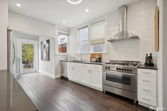 kitchen featuring appliances with stainless steel finishes, white cabinetry, sink, dark hardwood / wood-style flooring, and wall chimney exhaust hood