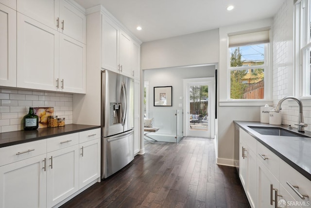 kitchen with sink, dark wood-type flooring, white cabinetry, stainless steel refrigerator with ice dispenser, and tasteful backsplash