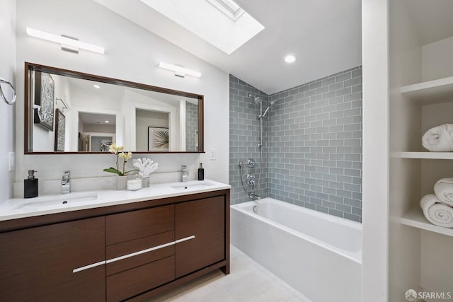 bathroom with tiled shower / bath, vanity, and vaulted ceiling with skylight