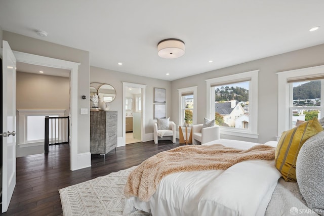 bedroom featuring multiple windows, dark hardwood / wood-style floors, and ensuite bath