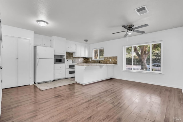 1607 California Dr, Vacaville, CA 95687 - kitchen featuring white appliances, a peninsula, white cabinetry, tasteful backsplash, and ceiling fan
