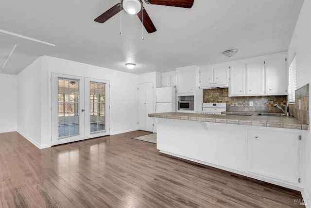 1607 California Dr, Vacaville, CA 95687 - kitchen featuring tile countertops, white appliances, under cabinet range hood, french doors, and a peninsula