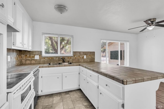 1607 California Dr, Vacaville, CA 95687 - kitchen featuring white electric stove, a peninsula, a ceiling fan, backsplash, and white cabinetry