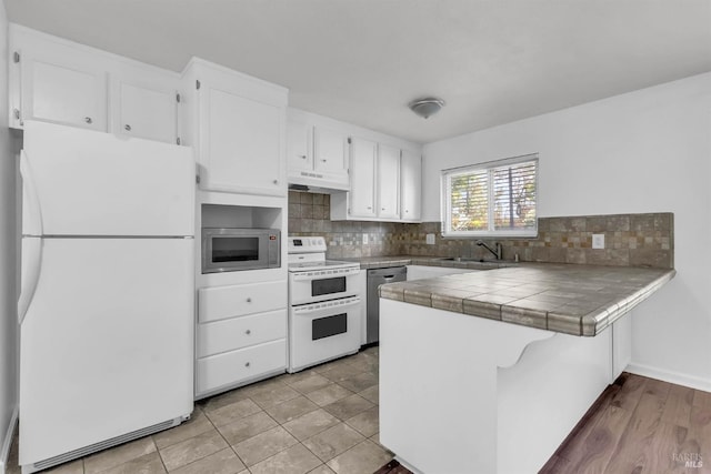1607 California Dr, Vacaville, CA 95687 - kitchen featuring white appliances, under cabinet range hood, a peninsula, white cabinetry, and backsplash