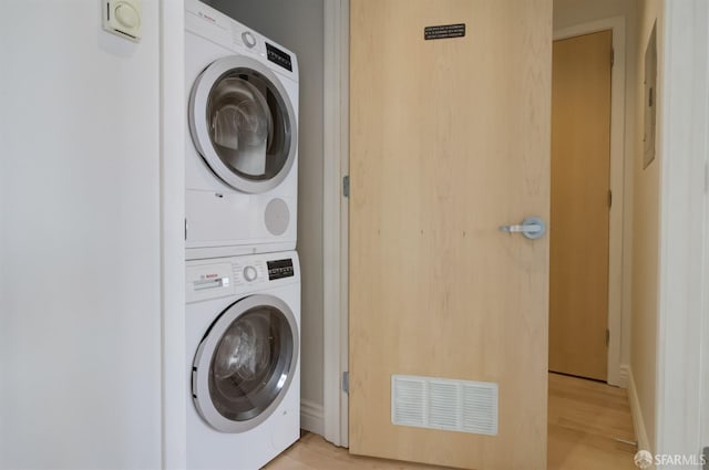 washroom featuring stacked washing maching and dryer and light hardwood / wood-style flooring