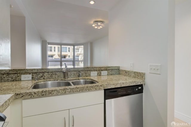 kitchen with light stone countertops, sink, white cabinets, and dishwasher