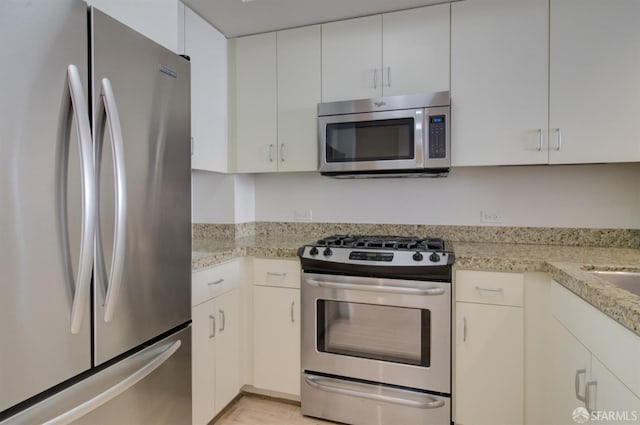 kitchen featuring light stone counters, white cabinetry, and appliances with stainless steel finishes