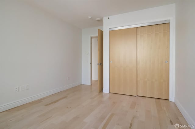 unfurnished bedroom with a closet and light wood-type flooring