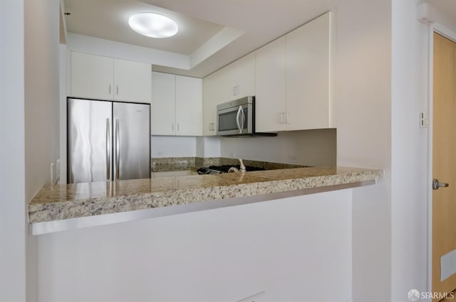 kitchen featuring white cabinetry, light stone counters, kitchen peninsula, and appliances with stainless steel finishes