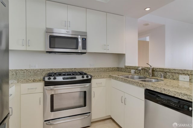 kitchen with sink, stainless steel appliances, light stone counters, and white cabinets