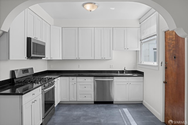 59 Collingwood St, San Francisco, CA 94114 - kitchen with appliances with stainless steel finishes, a sink, white cabinets, dark countertops, and arched walkways