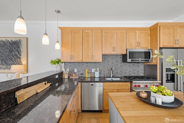 kitchen featuring appliances with stainless steel finishes, a sink, decorative backsplash, hanging light fixtures, and ornamental molding