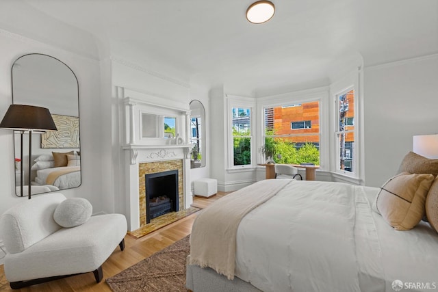 bedroom with a tile fireplace, wood finished floors, and baseboards